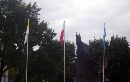 Flagi podniesione na trzech masztach przy pomniku Jana Pawła II w Łowiczu.